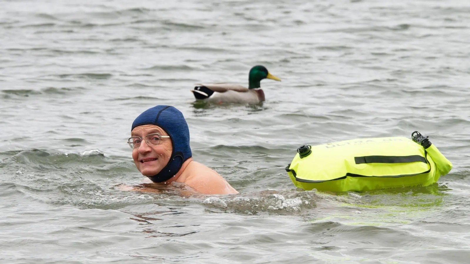 Comedian Wigald Boning schwimmt neben einer Ente in einem See. (Foto: Henning Kaiser/dpa/Archivbild)