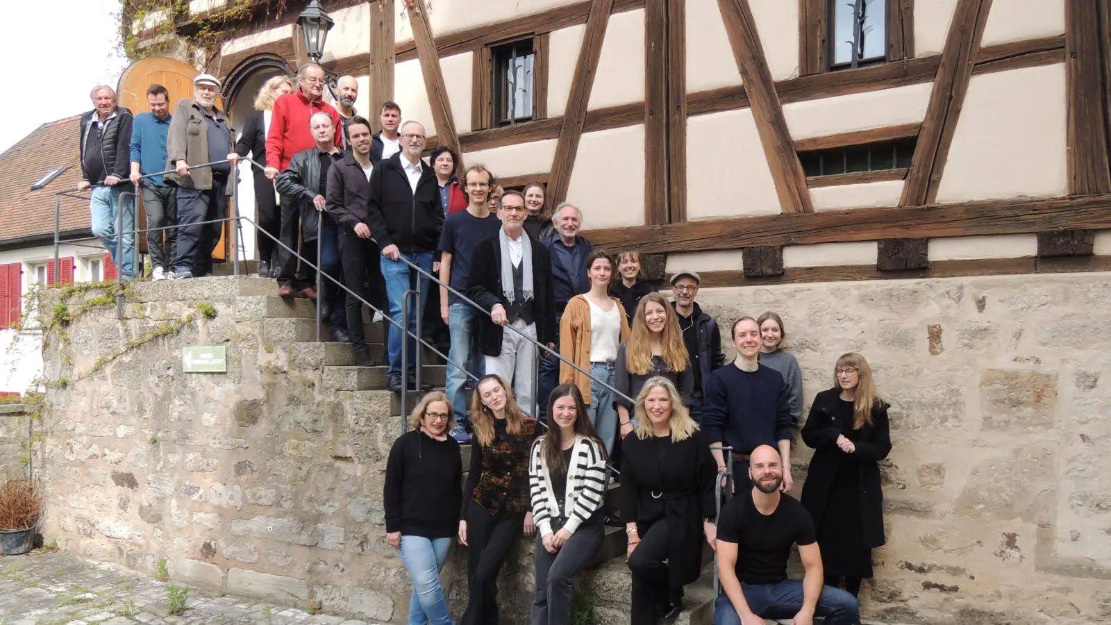 Die Proben für das Dürrenmatt-Stück „Der Besuch der alten Dame“ im Kreuzgang haben gestern begonnen. Zum Auftakt hieß Intendant und Regisseur Johannes Kaetzler (etwa in der Mitte auf der Außentreppe an der Stadthalle Kasten) das Ensemble in Feuchtwangen willkommen. (Foto: Peter Zumach)