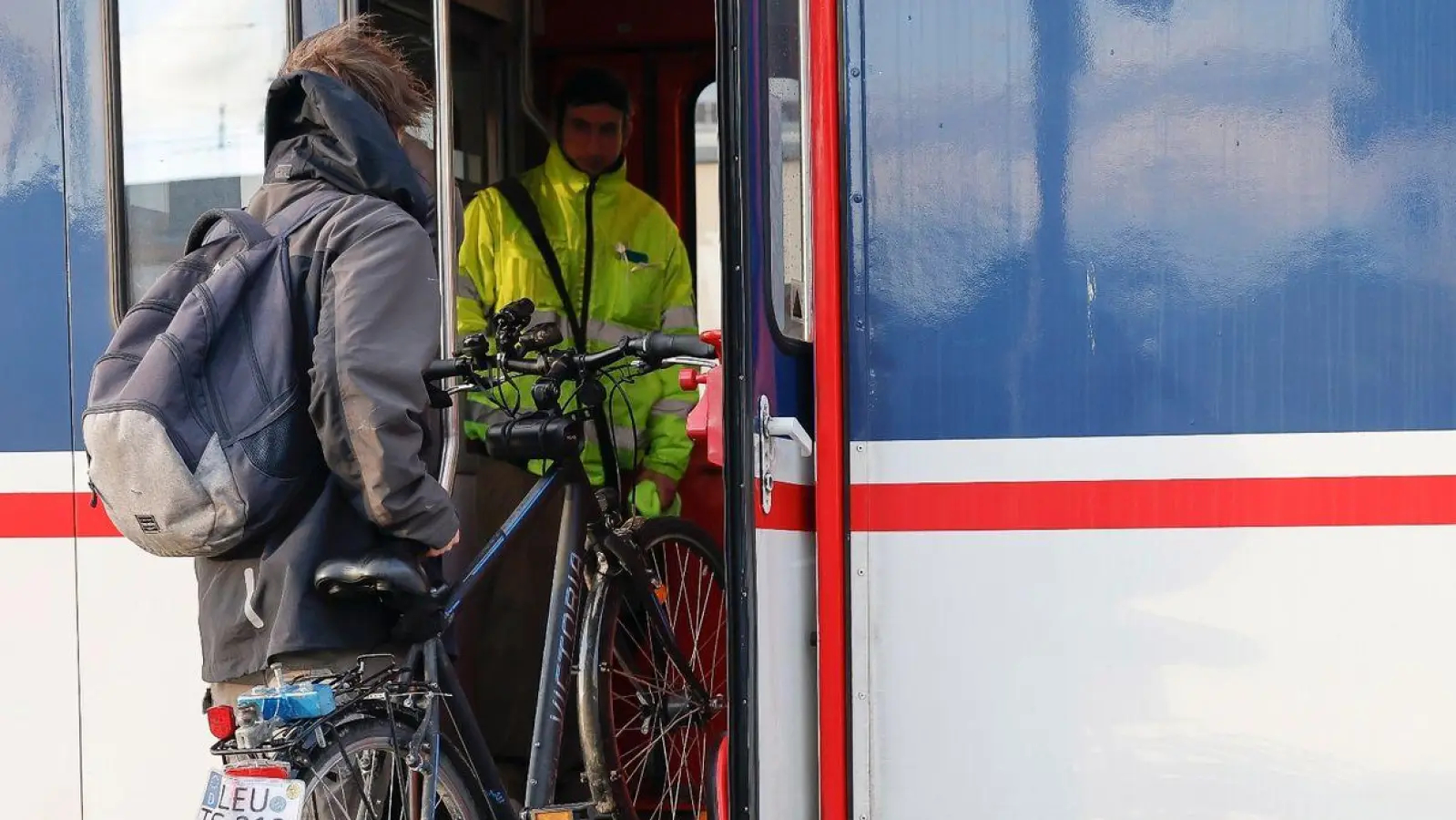 Ein Mann muss sein Fahrrad in den Zug heben. (Foto: Daniel Löb/dpa)