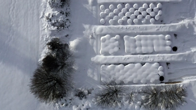 Schneebedeckte Silageballen liegen von einer Hecke umgeben auf einem Hof (Luftaufnahme mit einer Drohne). (Foto: Karl-Josef Hildenbrand/dpa)