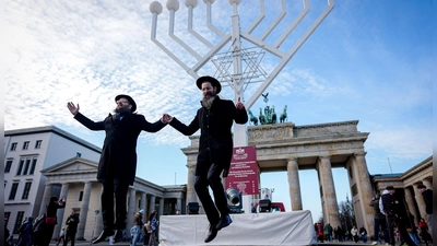 Yehuda Teichtal (l), orthodoxer Rabbiner, und Rabbi Shmuel Segal tanzen bei der Einweihung des Chanukka-Leuchters am Brandenburger Tor in Berlin. (Foto: Kay Nietfeld/dpa)