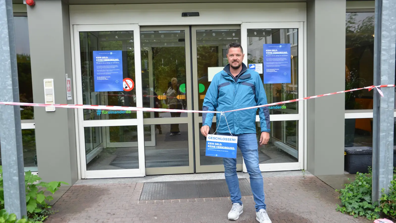 Der Marketingleiter der Kliniken im Landkreis, Benjamin Maier, stellte sich fürs Foto kurz hinter die symbolische Absperrung des Klinik-Haupteingangs.  (Foto: Christa Frühwald)