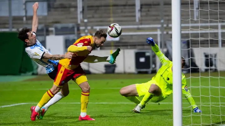 Lucas Cueto (M) von Karlsruhe spielt gegen Kevin Goden (l) und Torwart Marco Hiller von München den Ball ins Tor. (Foto: Sven Hoppe/dpa/Archivbild)