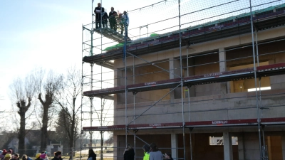 Vom Baugerüst in luftiger Höhe hielt Zimmerermeister Helmut Burger den Richtspruch. Die Gäste der Feier hörten bei herrlichem Winterwetter zu. (Foto: Walter Oberhäußer)