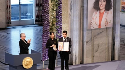 Kiana (l) und Ali Rahmani halten die Medaille und die Urkunde während der Verleihung des Friedensnobelpreises 2023 im Rathaus von Oslo. Die Zwillinge nehmen den Friedensnobelpreis stellvertretend für ihre inhaftierte Mutter entgegen. (Foto: Fredrik Varfjell/NTB/dpa)