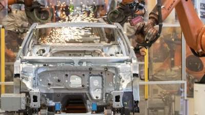 Teile eines VW Passat werden im Karosseriewerk von VW von Kuka-Robotern zusammengefügt. (Foto: Jörg Sarbach/dpa)