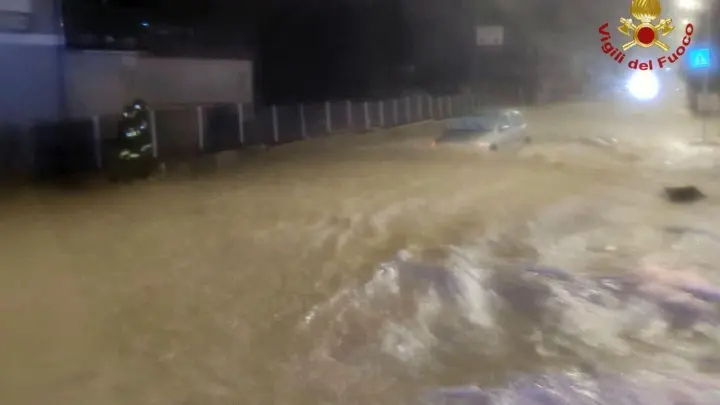 Auf einer überfluteten Straße treibt ein Auto durch die Wassermassen. (Foto: Vigili del Fuoco/dpa)