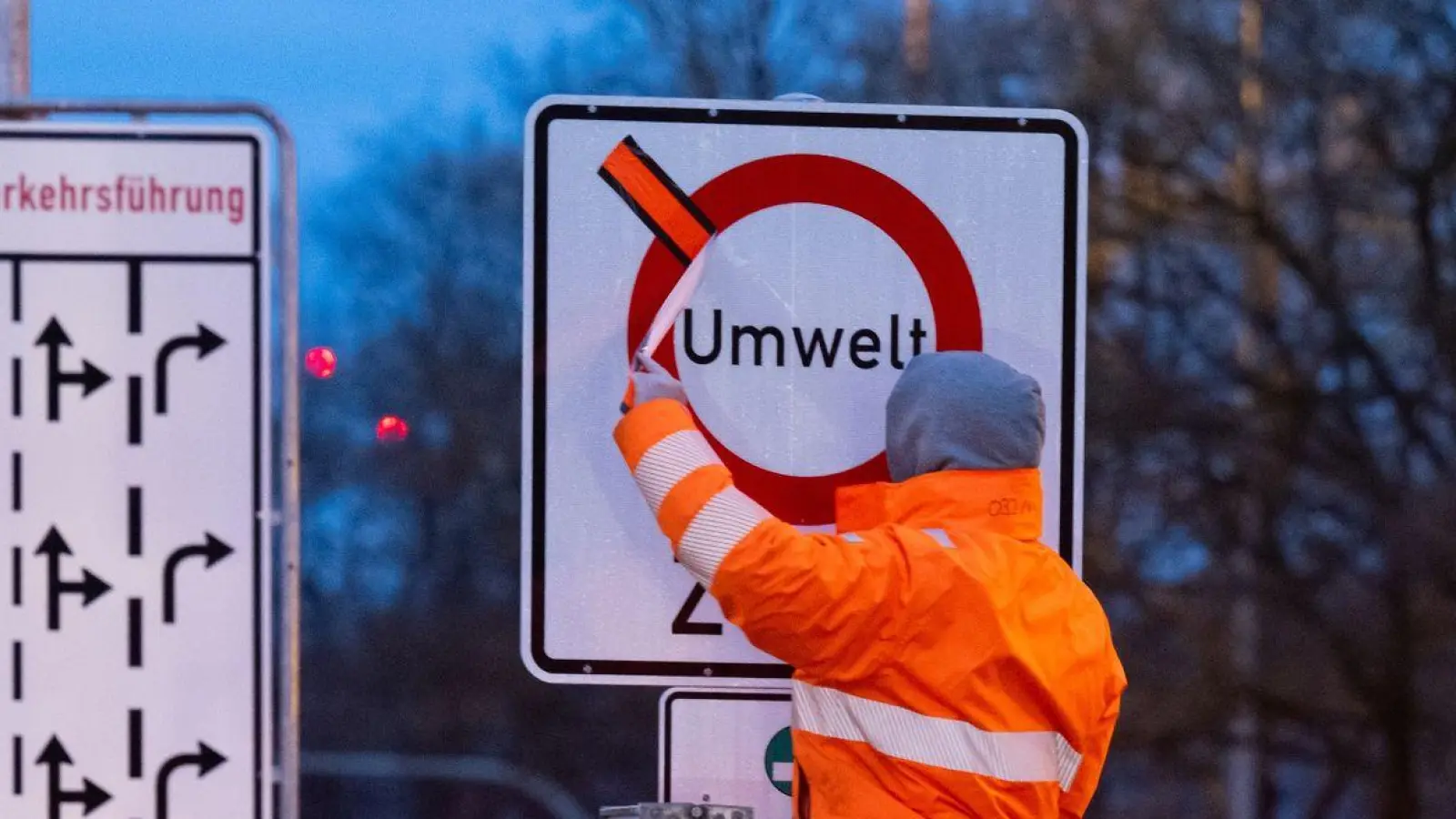 Arbeiter entfernen einen roten Klebestreifen von einem Schild mit der Aufschrift „Umwelt Zone“. (Foto: Sven Hoppe/dpa/Archivbild)