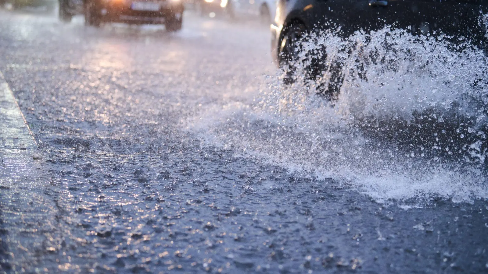 Autos fahren bei starkem Regen durch tiefe Pfützen. (Foto: Annette Riedl/dpa/Symbolbild)