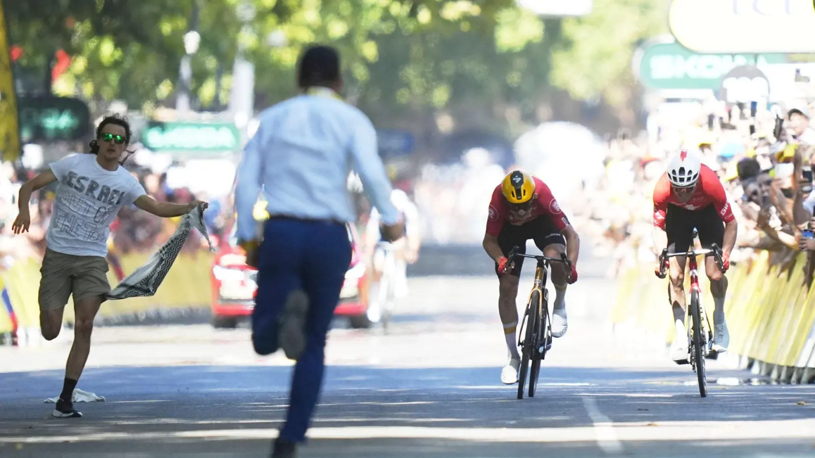 Während Jonas Abrahamsen und Mauro Schmid (r) in Toulouse um den Sieg sprinten, läuft ein Flitzer (l) auf die Zielgerade. (Foto: Thibault Camus/AP/dpa)