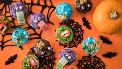 Da können sich kleine Halloweenjünger schon im Vorfeld der Party kreativ austoben: Mit Frischkäse-Frosting, Lebensmittelfarben und Zuckerdekor lassen sich putzige Monster-Muffins zubereiten. (Foto: Christin Klose/dpa-tmn)