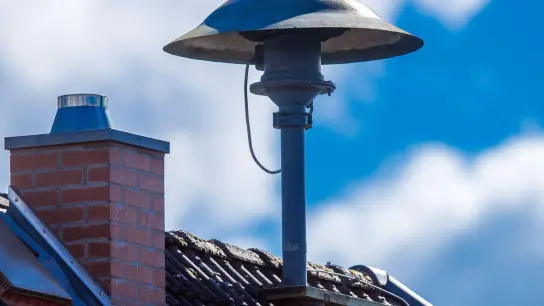Eine Alarmsirene steht auf einem Hausdach. (Foto: Jens Büttner/dpa-Zentralbild/dpa)