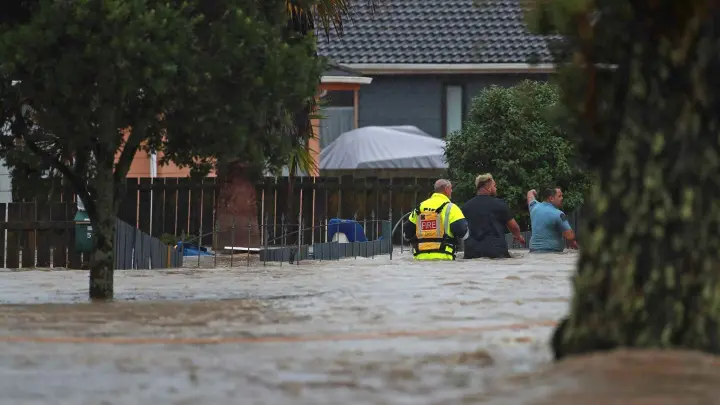 Menschen waten durch das Hochwasser einer vollkommen überschwemmten Straße in Auckland. (Foto: Hayden Woodward/New Zealand Herald/AP/dpa)