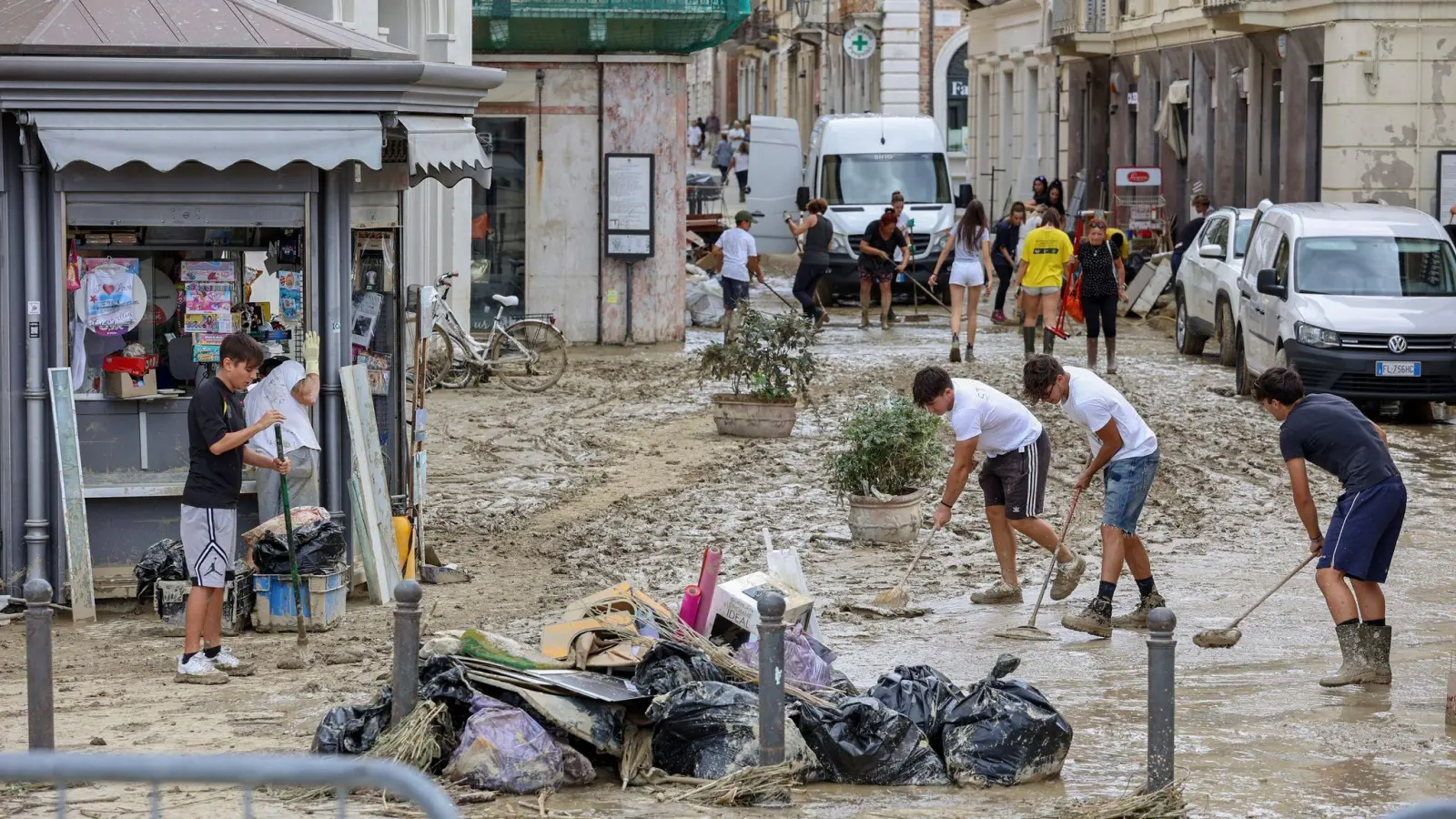 Junge Leute entfernen Schlamm von einer Straße in Senigallia. Durch heftige Regenfälle ausgelöste Sturzfluten haben Städte im hügeligen Mittelitalien überschwemmt. (Foto: Guido Calamosca/LaPresse via AP/dpa)