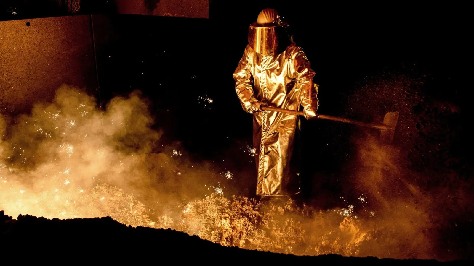 Ein Mitarbeiter schaufelt in einem Stahlwerk Sand in die Abstichrinne am Hochofen. Die Bundesregierung kann der deutschen  Stahlindustrie beim Umbruchin eine klimafreundlichere Zukunft helfen. (Foto: Hauke-Christian Dittrich/dpa)