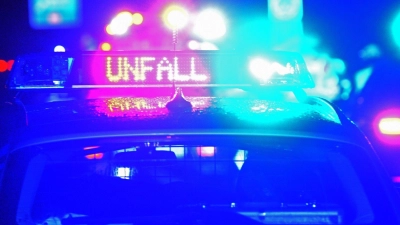 Das Blaulicht und der LED-Schriftzug „Unfall“ spiegeln sich auf dem nassen Dach eines Polizeiwagens. (Symbolbild: Stefan Puchner/dpa)