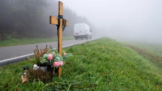 Ein Holzkreuz zum Gedenken wurde am Tatort an der K22 bei Kusel aufgestellt, wo Ende Januar 2022 zwei Polizisten im Dienst getötet wurden. (Foto: Harald Tittel/dpa)