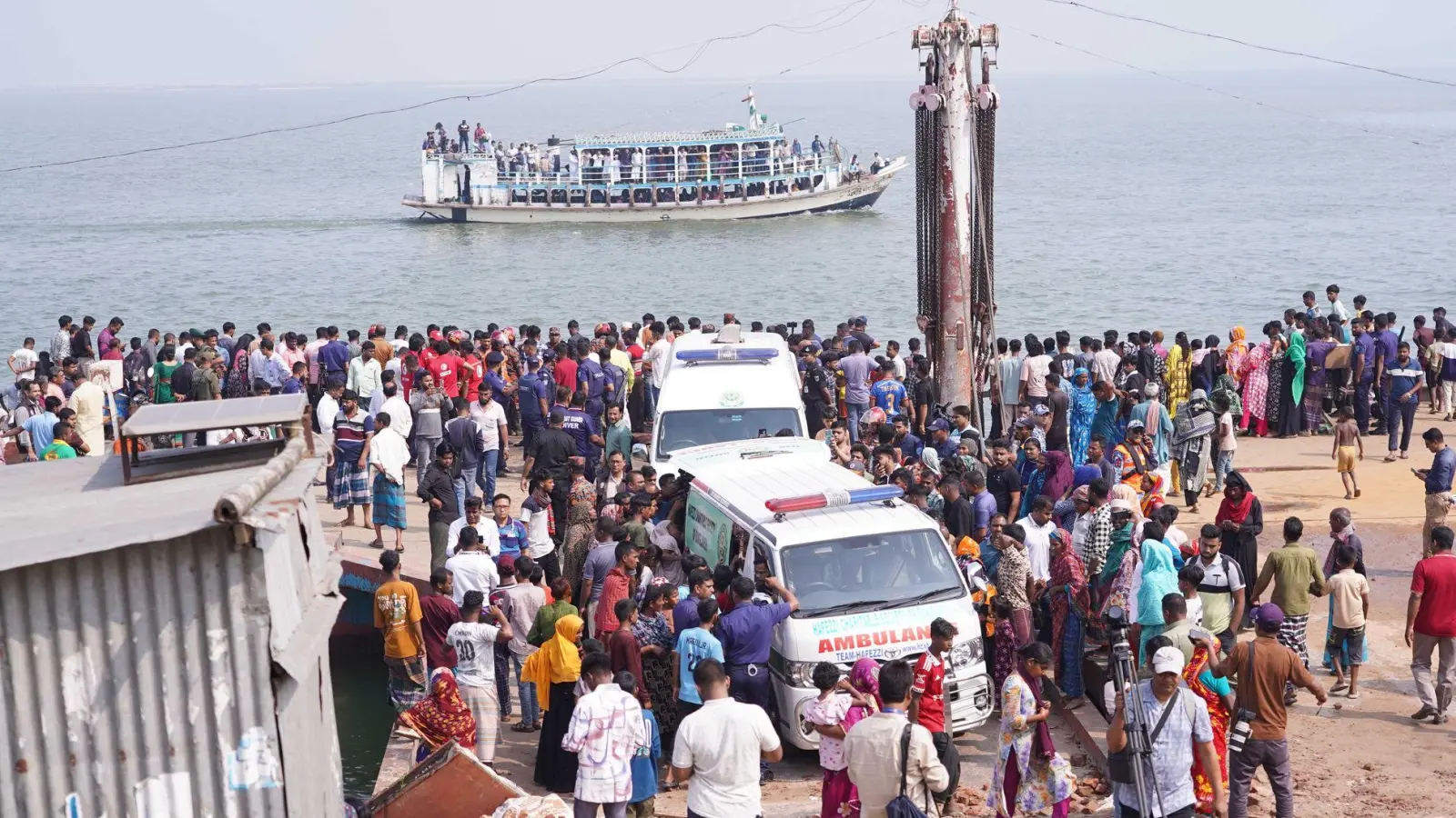 Rettungskräfte und zahlreiche Menschen versammeln sich an einer Unfallstelle, nachdem ein Bus in den Fluss Padma stürzte. (Foto: Rubel Karmaker/ZUMA Press Wire/dpa)
