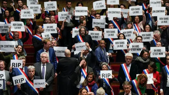 Die umstrittene Rentenreform in Frankreich ist trotz heftiger Proteste beschlossen - linke Abgeordnete reagieren in der Nationalversammlung mit Protestparolen. (Foto: Lewis Joly/AP/dpa)