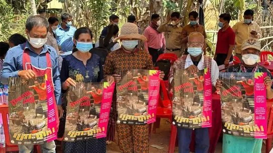 Dorfbewohner in der östlichen Provinz Prey Veng mit Plakaten, die auf die Bedrohung durch das Vogelgrippevirus aufmerksam machen. (Foto: Cambodia Ministry of Health/AP/dpa)