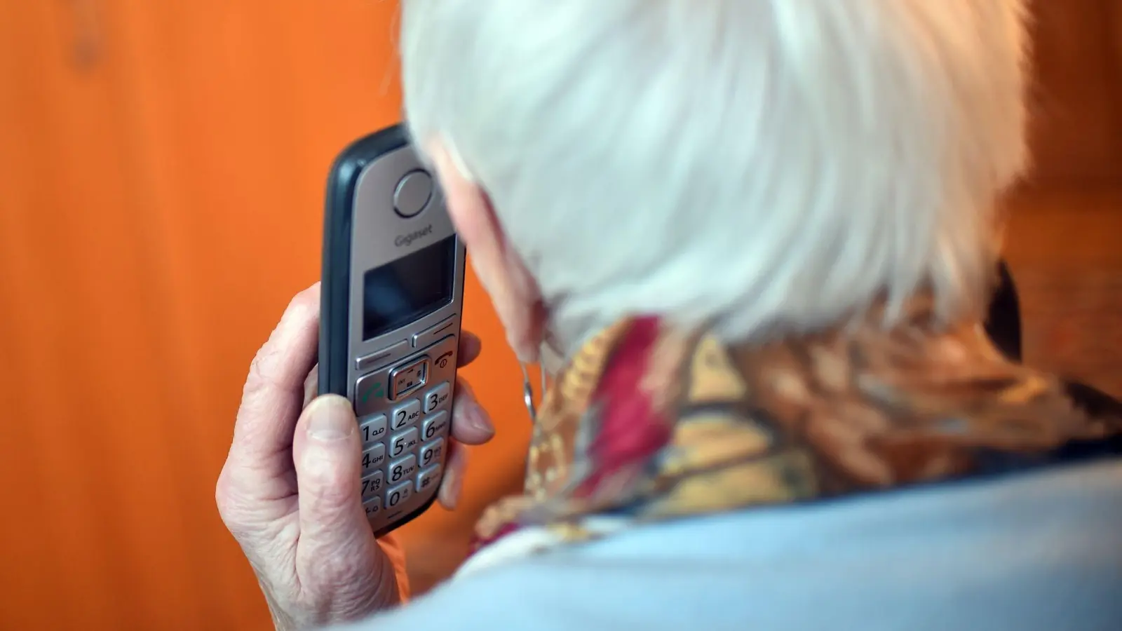 Eine Seniorin hält einen Telefonhörer an ihr Ohr. (Foto: Britta Pedersen/zb/dpa/Symbolbild)