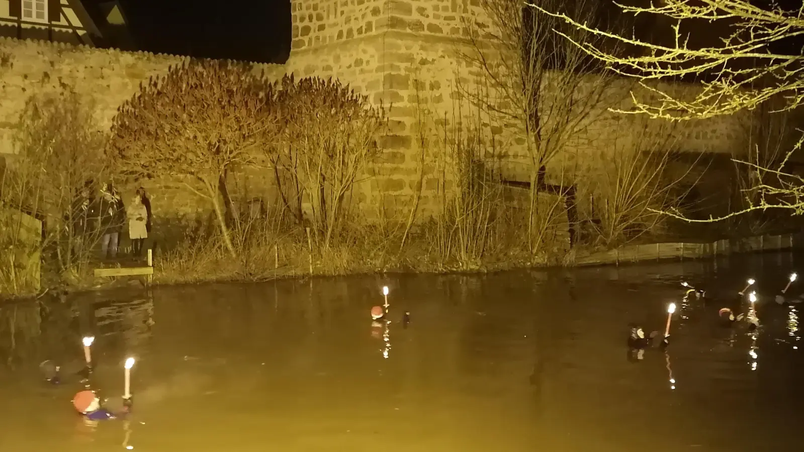 Vor Dinkelsbühls Stadtmauer als imposanter Kulisse: Bei einer Wassertemperatur um die sechs Grad legten die Fackel-Schwimmer rund einen Kilometer in der Wörnitz zurück. (Foto: Friedrich Zinnecker)