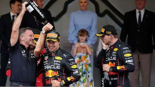 Sergio Perez aus Mexiko (M) feiert seinen Sieg in Monaco mit Red-Bull-Teamchef Christian Horner Teamkollege Max Verstappen. (Foto: Daniel Cole/AP/dpa)