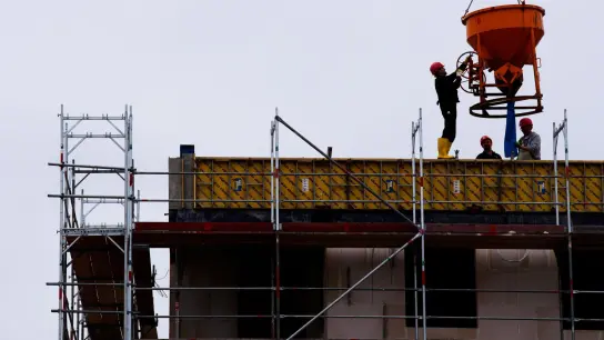 Arbeiter stehen auf einer Baustelle eines Wohngebäudes. (Foto: Soeren Stache/dpa-zentralbild/dpa/Symbolbild)
