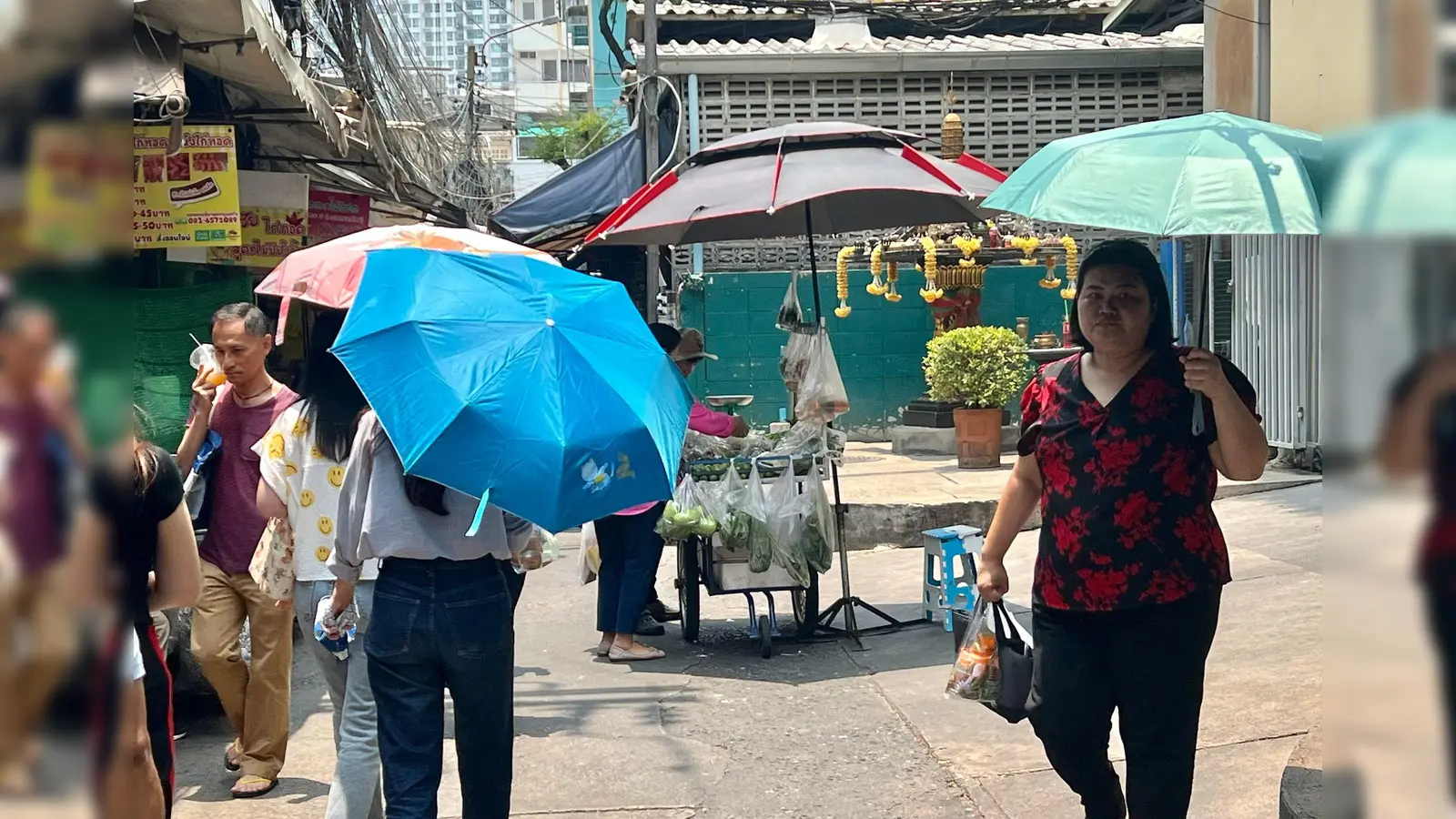 Menschen schützen sich in Bangkok mit Schirmen vor der extremen Hitze und vor der Sonne. (Foto: Carola Frentzen/dpa)
