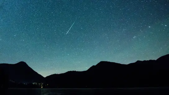 Eine Sternschnuppe leuchtet neben der Milchstraße am Himmel über dem Walchensee. (Foto: Matthias Balk/dpa)