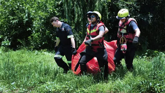 Rettungskräfte tragen die Leiche eines Überschwemmungsopfers, das aus dem Fluss Jukskei geborgen wurde. (Foto: -/AP/dpa)