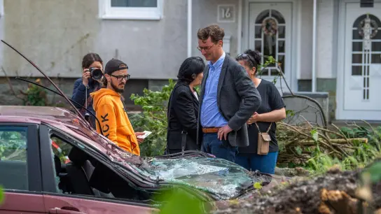 Hendrik Wüst (CDU, 2.v.r.), Ministerpräsident von Nordrhein Westfalen, spricht in Lippstadt mit einem Anwohner, dessen Auto durch den Sturm zerstört wurde. (Foto: Lino Mirgeler/dpa)