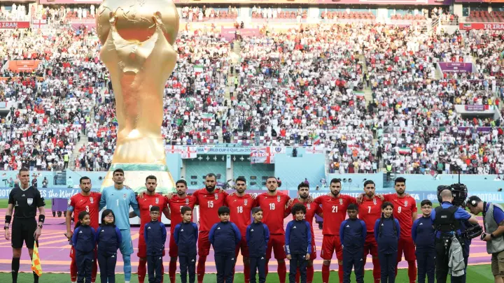 Spieler des Iran stehen beim Abspielen der Nationalhymne vor dem übergroßen Weltpokal im Stadion in Katar. (Foto: Han Yan/XinHua/dpa)