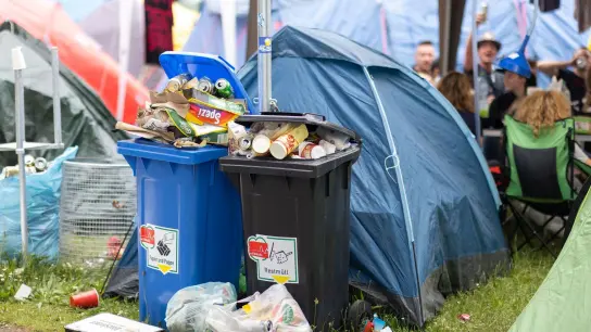Überfüllte Mülltonnen stehen auf dem Campingplatz. (Foto: Daniel Karmann/dpa/Archivbild)
