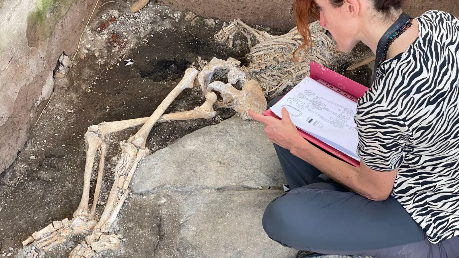 Eine Frau sitzt vor einem Skelett im Archäologiepark Pompeji. (Foto: -/Archäologiepark Pompeji/dpa)