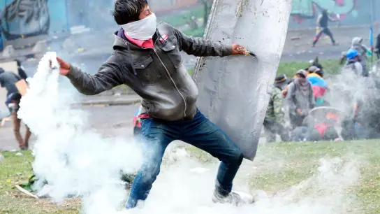 Ein Demonstrant wirft bei Zusammenstößen in der Innenstadt von Quito eine Tränengasgranate zurück auf Polizisten. (Foto: Dolores Ochoa/AP/dpa)