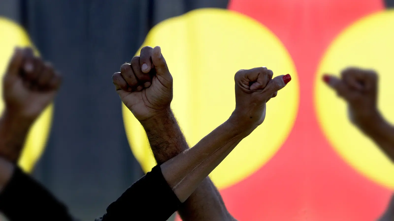 Ein Mann und eine Frau verschränken die Arme vor einer Aborigines-Flagge während einer Kundgebung der Bewegung „Black Lives Matter“ in Sydney (Symbolbild). Der „Sydney Morning Herald“ hat sich für seine Berichterstattung zum Myall-Creek-Massaker entschuldigt. (Foto: Rick Rycroft/AP/dpa)