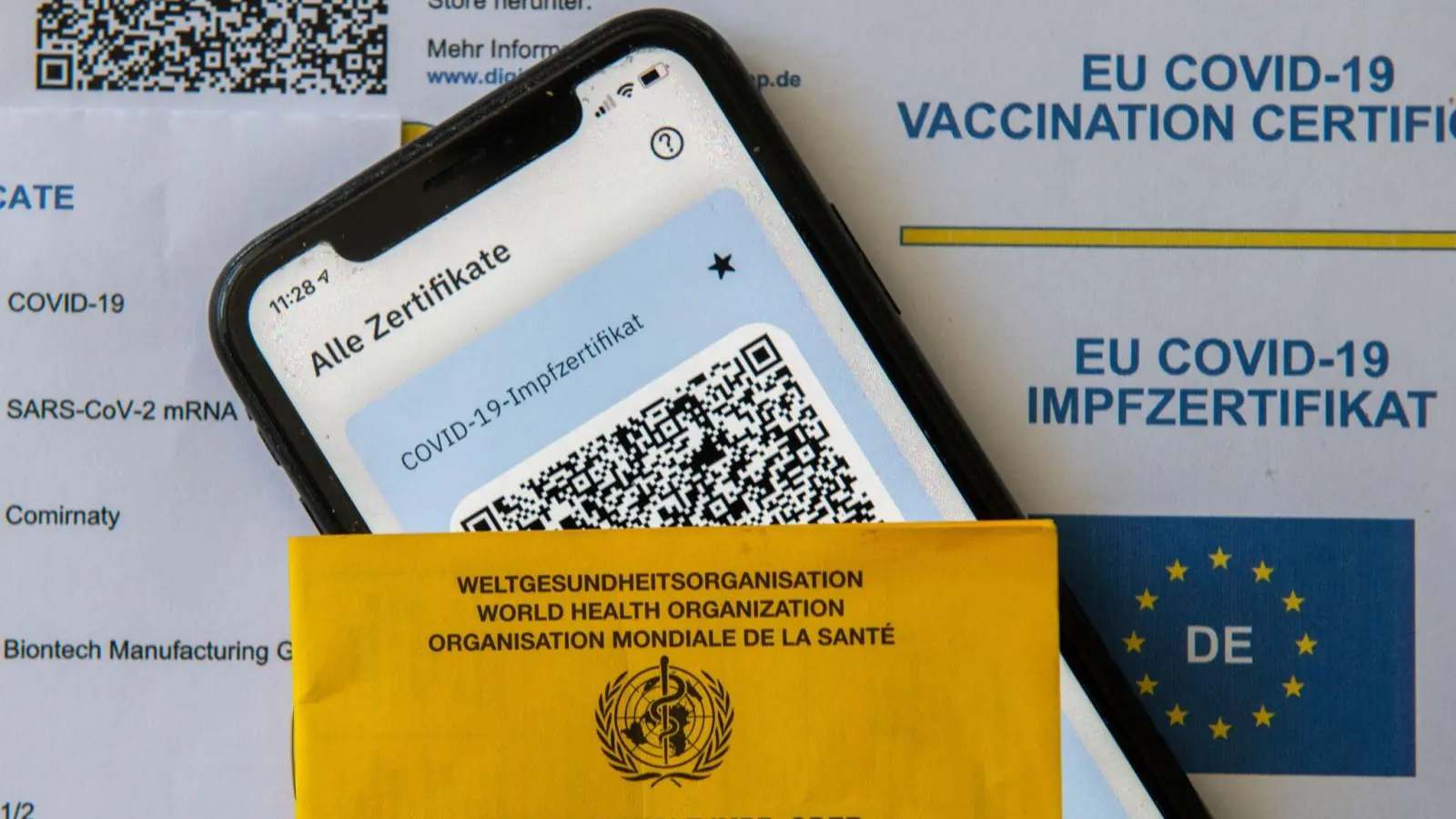 Ein Impfpass und ein Smartphone mit der CovPass-App liegen auf einem Impfzertifikat. (Foto: Stefan Puchner/dpa/Symbolbild)