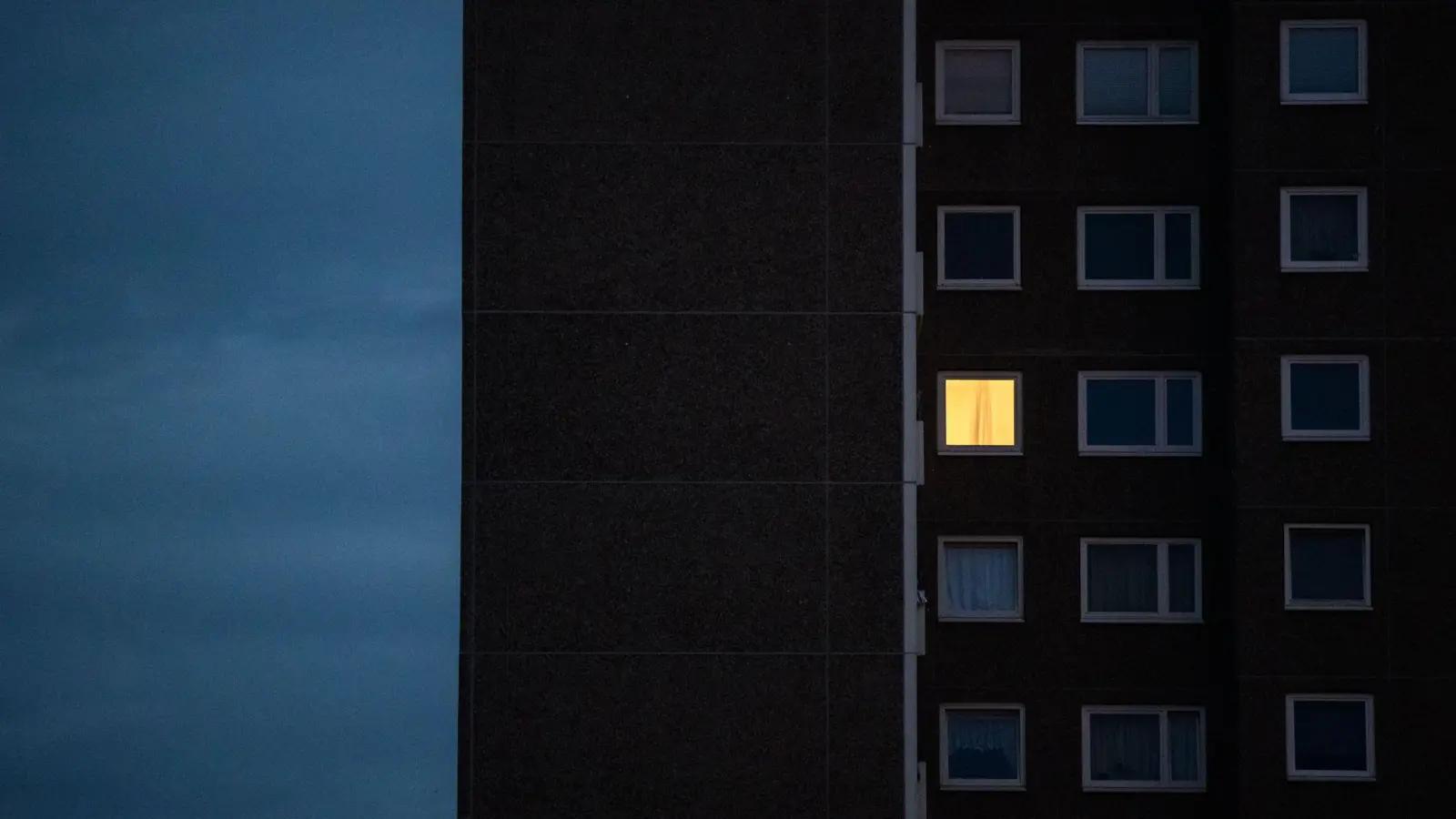 Licht brennt nur in einer Wohnung eines Mehrfamilienhauses. (Foto: Julian Stratenschulte/dpa/Symbolbild)