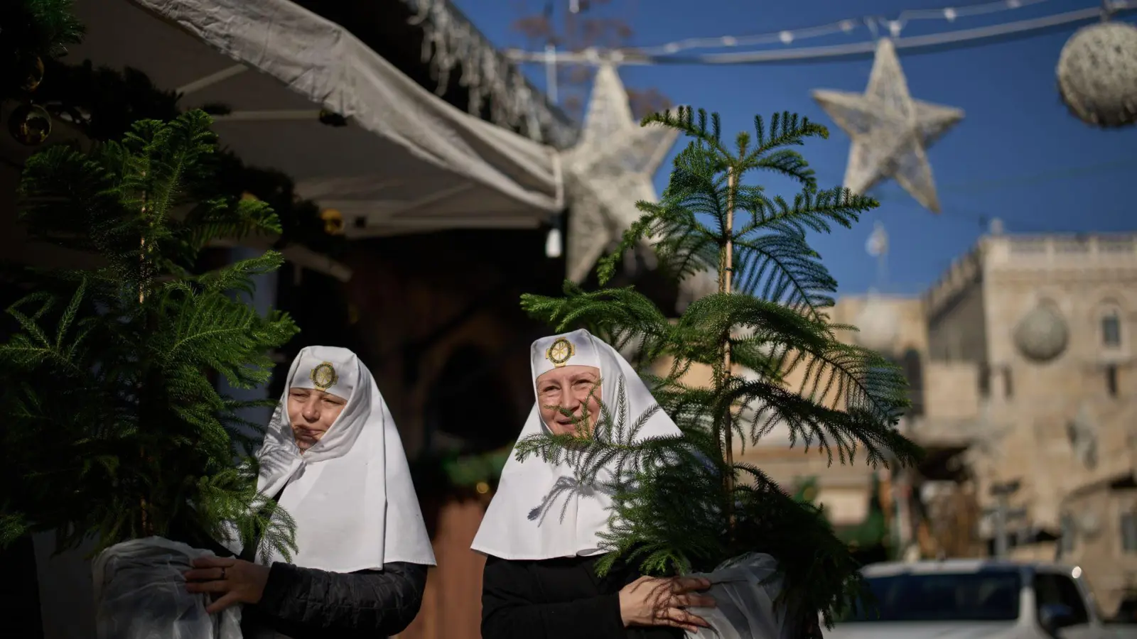 Orthodoxe Christinnen holen Weihnachtsbäume in Jerusalems Altstadt ab (Foto: Leo Correa/AP/dpa)