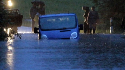 Ein Fahrzeug steht von Wasser umgeben auf einer überfluteten Straße am Bodensee. (Foto: Bernd März/dpa)