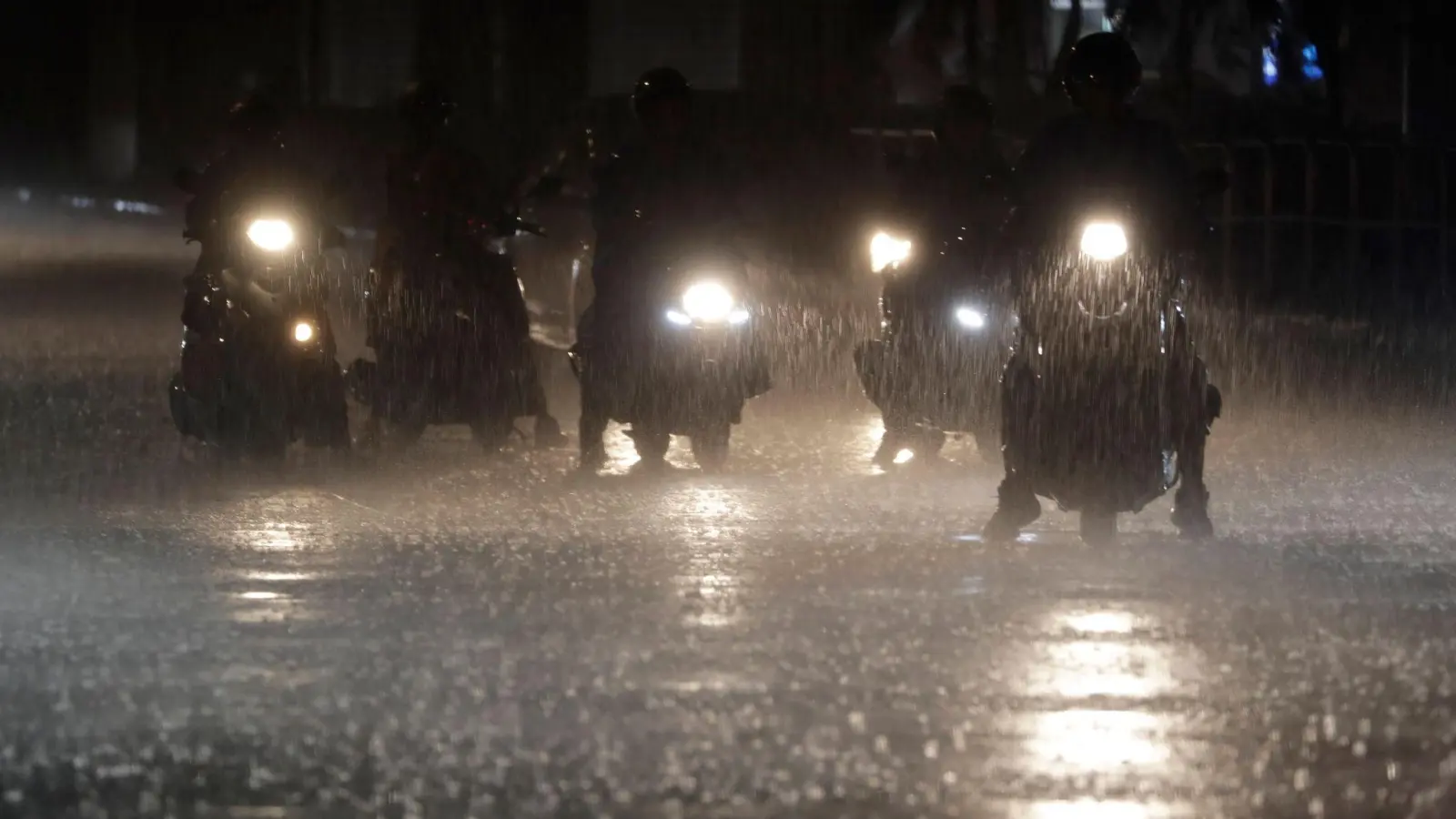 Rollerfahrer stehen bei heftigem Regen an einer Kreuzung in Taipeh. (Foto: Chiang Ying-ying/AP)