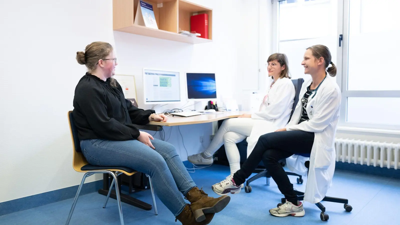 Judith Lohse (r), Kinderärztin, und Katharina Egger-Heidrich, Fachärztin Onkologie, sitzen mit einer Patientin im Nationalen Centrum für Tumorerkrankungen in einem Behandlungsraum. (Foto: Sebastian Kahnert/dpa)
