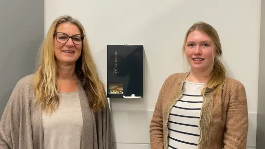 Studierende und Mitarbeitende brachten die Spender gemeinsam auf den Weg: Birgit Kasper und Anna Buchberger (v. l.) zeigen einen der Automaten mit Binden und Tampons. (Foto: privat)
