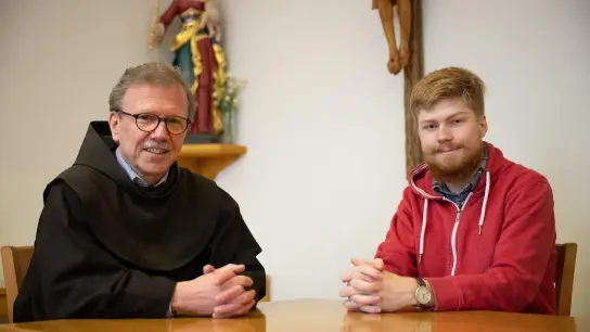 Peter Roberg (r) und Pater Cornelius Bohl, Guardian des Klosters Frauenberg, sitzen im Franziskanerkloster Frauenberg nebeneinander. (Foto: Sebastian Gollnow/dpa)