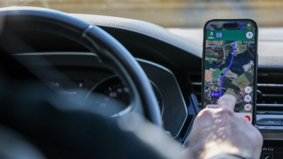 So ist es derzeit erlaubt: Das Handy steckt in der Halterung und wird nur kurz vom Fahrer beachtet. (Symbolbild) (Foto: Jan Woitas/dpa)