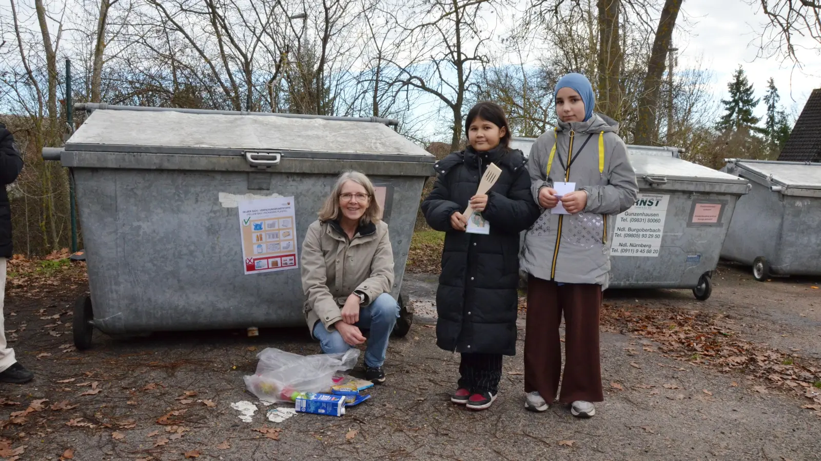 Leere Plastikverpackungen kommen in den gelben Sack: Mittelschullehrerin Gudrun Mehringer sowie die Sechstklässlerinnen Farida Hosseini (Mitte) und Makka Khamzaeva erklärten den Bewohnerinnen und Bewohnern der Unterkunft Kopernikusstraße die Mülltrennung.  (Foto: Yvonne Neckermann)