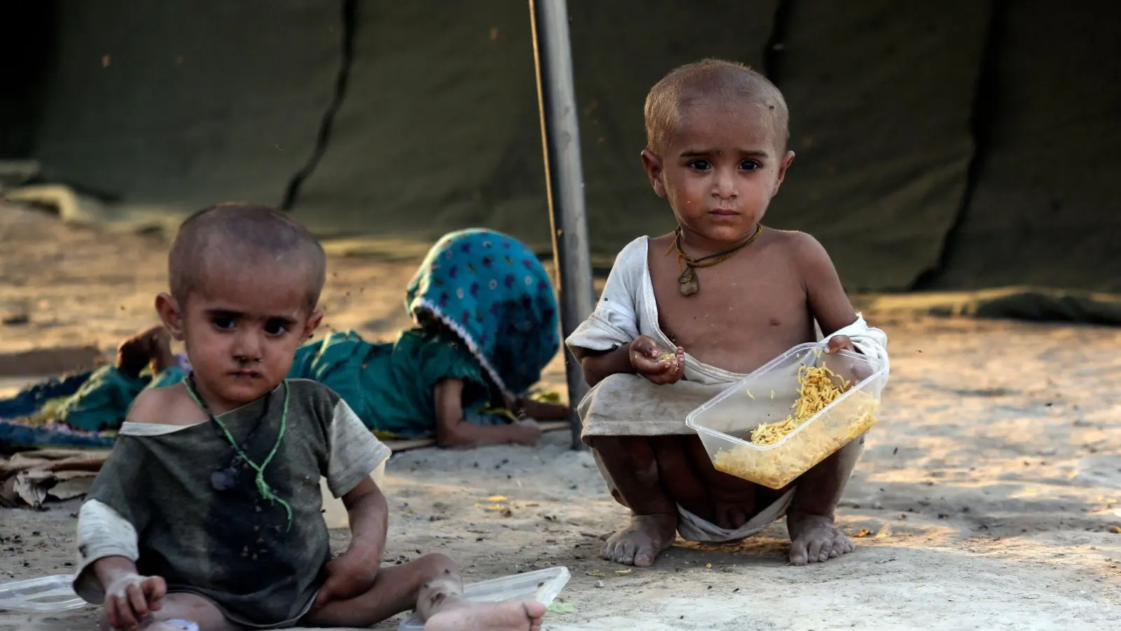 Kleinkinder, die durch die Überschwemmungen des Monsuns vertrieben wurden, essen in einem provisorischen Zeltlager für Flutopfer im pakistanischen Sukkur. (Foto: Fareed Khan/AP/dpa)