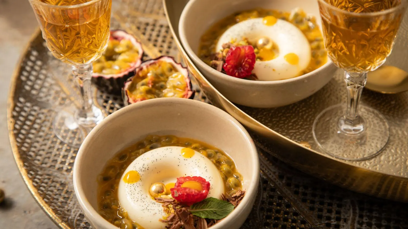 Panna Cotta mit Passionsfrucht, Himbeere, Mangotupfer, Minze, Pistazie, Schokolade und goldenen Schokokugeln in Savarin-Form zubereitet. Das ist eine Backform in flacher, ringförmiger Gestalt.   (Foto: Christin Klose/dpa-tmn)