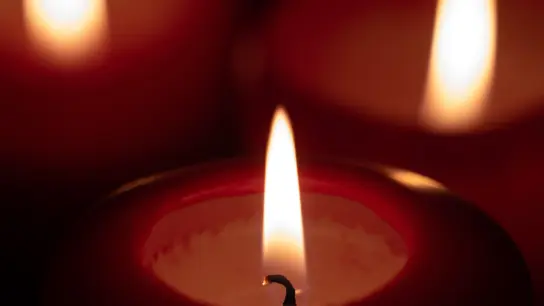 Drei Kerzen brennen in einem dunklen Raum. (Foto: Sebastian Gollnow/dpa)